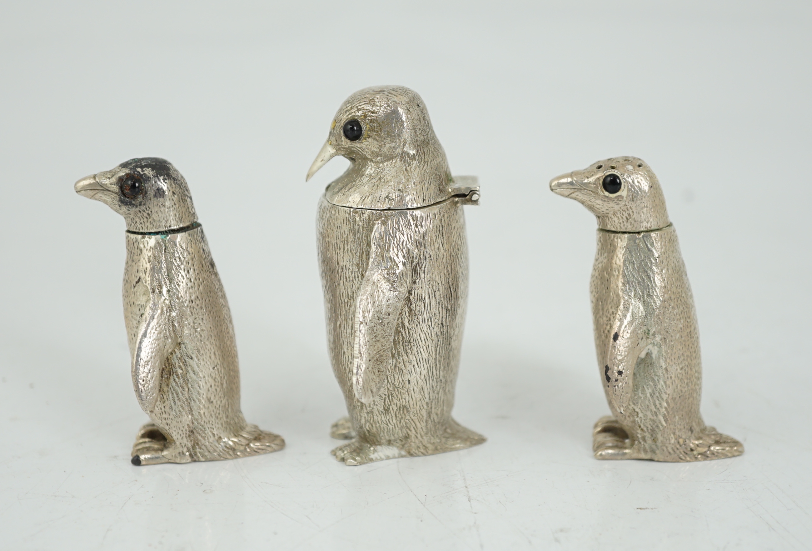 An Elizabeth II graduated suite of three novelty silver condiments, modelled as penguins, by William Comyns & Sons Ltd